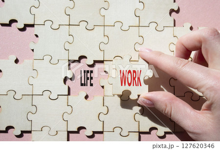 Life or Work symbol. Concept word Life or Work on wooden puzzle. Businessman hand. Beautiful pink background. Business and Life or Work concept. Copy space Life or Work symbol. Concept word Life or Work on wooden puzzle. Businessman hand. Beautiful pink background. Business and Life or Work concept. Copy space 127620346