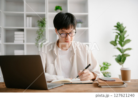 Portrait of a Asian young man sitting at his desk in the office. 127621240