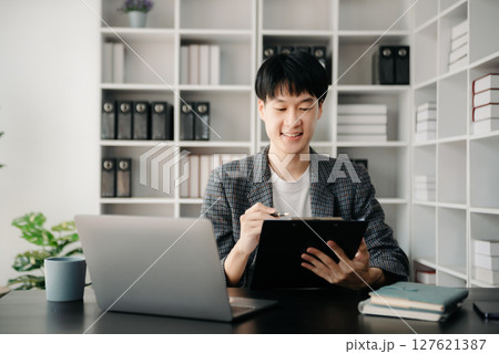 Portrait of young man sitting at his desk in the office Portrait of young man sitting at his desk in the office 127621387
