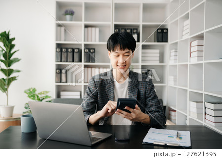 Portrait of young man sitting at his desk in the office 127621395