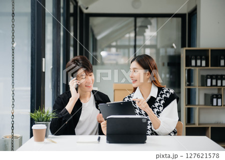 Two Asian businesswoman and man discuss investment project working and planning strategy with tablet laptop computer in office. Two Asian businesswoman and man discuss investment project working and planning strategy with tablet laptop computer in office. 127621578
