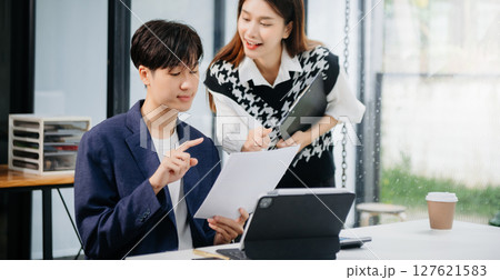 Two Asian businesswoman and man discuss investment project working and planning strategy with tablet laptop computer in office. 127621583