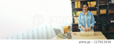Banner Online seller Close up hands Young asian woman typing laptop keyboard checking online order on stock delivery package. Asian woman startup small business at home office with copy space 127621636