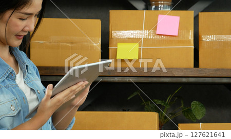 Asian woman startup small business at home office. Online seller entrepreneur young asian woman use tablet checking online order. Woman using tablet check stock goods supply delivery package shipping Asian woman startup small business at home office. Online seller entrepreneur young asian woman use tablet checking online order. Woman using tablet check stock goods supply delivery package shipping 127621641