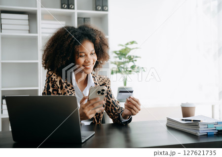 Successful African Businesswoman Analyzing Finance on Tablet and Laptop at modern Office Desk tax, 127621735