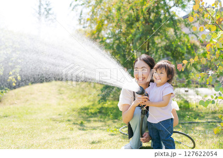 庭に水撒きをする親子 127622054