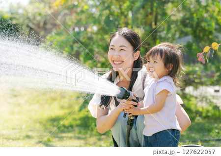 庭に水撒きをする親子 127622057