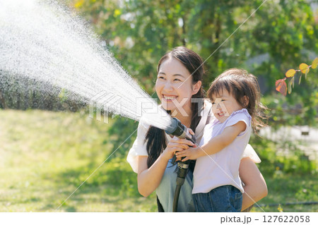 庭に水撒きをする親子 127622058