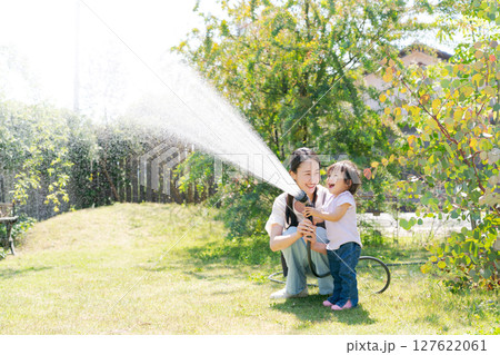 庭に水撒きをする親子 127622061