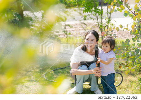 庭に水撒きをする親子 127622062