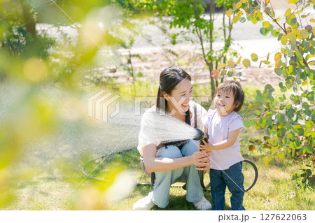 庭に水撒きをする親子 127622063