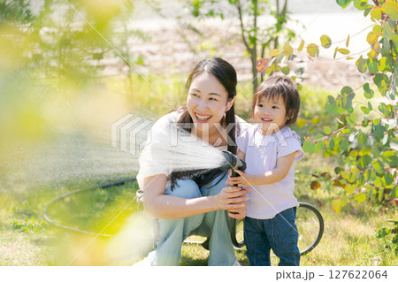 庭に水撒きをする親子 127622064