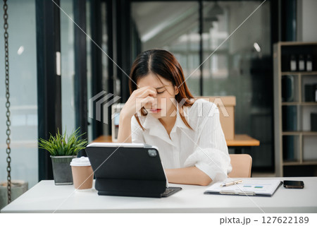 Frustrated young businesswoman working on a laptop computer sitting at his working place in office Frustrated young businesswoman working on a laptop computer sitting at his working place in office 127622189