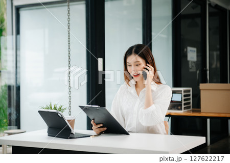 Asian businesswoman working in the office with working notepad, tablet and laptop documents Asian businesswoman working in the office with working notepad, tablet and laptop documents 127622217