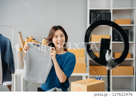 Young woman running online store Startup small business SME, using smartphone or tablet taking receive and checking online purchase shopping 127622476