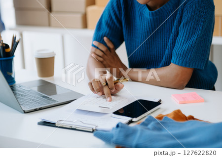 Young woman running online store Startup small business SME, using smartphone or tablet taking receive and checking online purchase shopping order Young woman running online store Startup small business SME, using smartphone or tablet taking receive and checking online purchase shopping order 127622820