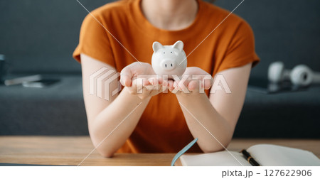 Women are putting coins in a piggy bank for a business that grows for profit and saving money for the future. planning for retirement concept 127622906