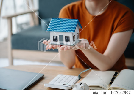Real estate broker agent presenting to customer to decision making sign insurance form agreement, buy and sell home model, concerning mortgage loan offer 127622907