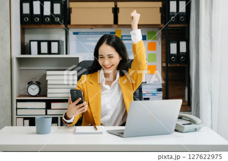 Asian business woman are delighted and happy with the work they do on their tablet, laptop and taking notes at the office. 127622975
