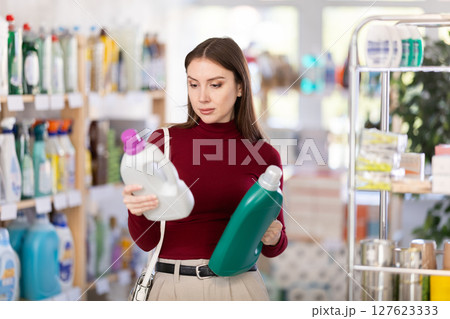 Young woman buyer chooses detergent in store Young woman buyer chooses detergent in store 127623333