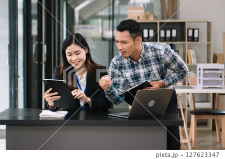 Happy businesspeople while collaborating on a new project in an office. diverse businesspeople using a laptop and tablet 127623347
