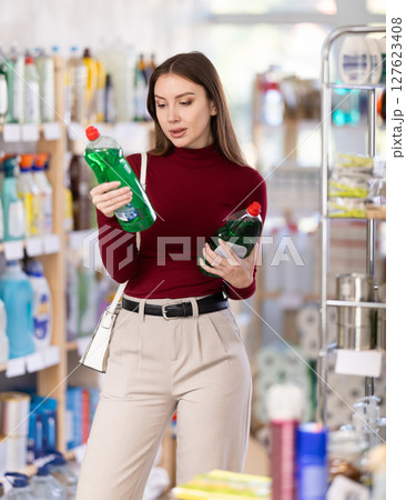 Young woman chooses dishwashing detergent in store Young woman chooses dishwashing detergent in store 127623408