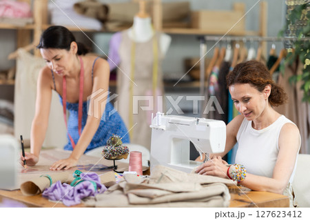 Woman tailor draw dress pattern with curve ruler on paper, female master seamstress sewing Woman tailor draw dress pattern with curve ruler on paper, female master seamstress sewing 127623412