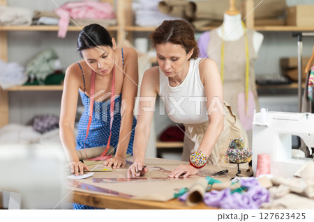 Women tailor draw dress pattern with curve ruler on paper 127623425