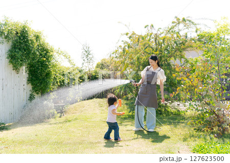 庭に水撒きをする親子 127623500