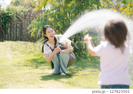 庭に水撒きをする親子 127623501