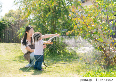 庭に水撒きをする親子 127623502
