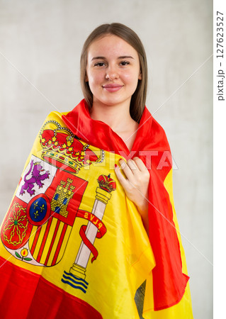 Portrait of young female supporter of the Spanish team wearing national flag 127623527
