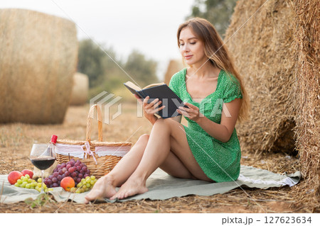 Woman in dress sitting reading book during picnic 127623634