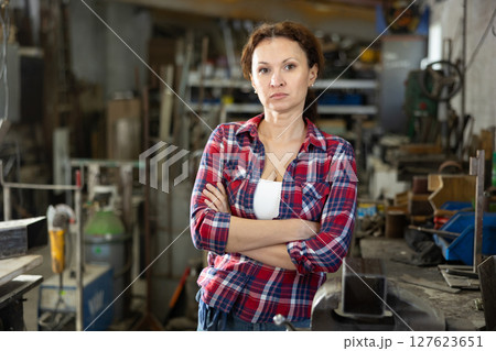 Portrait of confident female worker in workshop of metallurgical plant Portrait of confident female worker in workshop of metallurgical plant 127623651