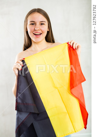 Reliant positive young woman holds big national flag of Belgium with confident smile 127623782