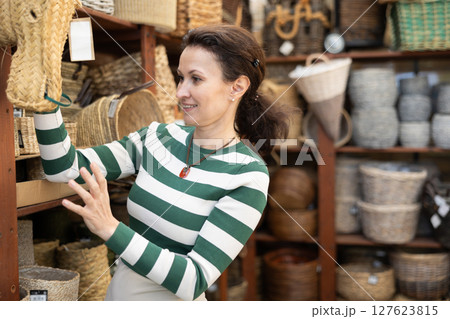 Woman choosing a wicker basket at hardware store Woman choosing a wicker basket at hardware store 127623815
