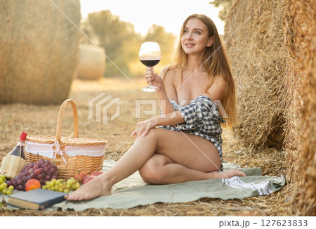 Woman in shirt sitting with wine during picnic 127623833