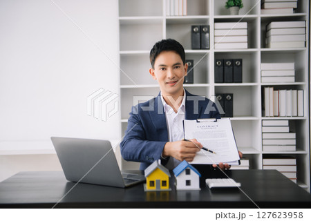 Asian man working with House model real estate agent and customer discussing for contract to buy house, insurance or loan real estate consult concerning mortgage loan offer Asian man working with House model real estate agent and customer discussing for contract to buy house, insurance or loan real estate consult concerning mortgage loan offer 127623958
