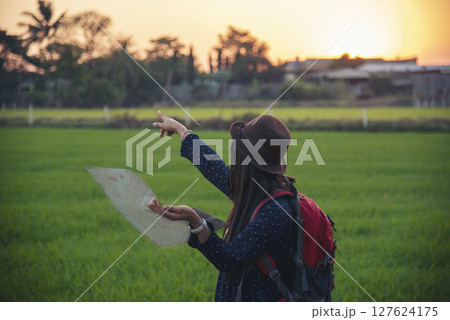 Women outdoor travel lifestyle Asian young woman traveler backpack looking map in green nature park. Female tourist backpacker holding brochure on vacation. Happy Tourism trip women journey walk park 127624175