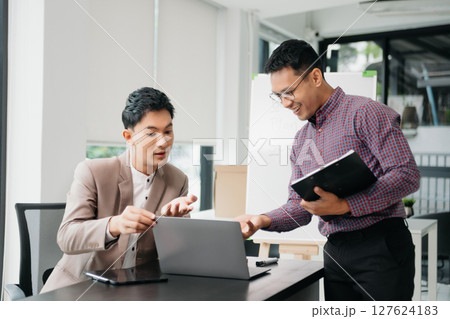 working together on a project two young business colleagues working on a computer at modern office 127624183