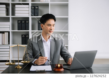 Attractive young lawyer in office Business man and lawyers discussing contract papers laptop and tablet with brass scale on  desk in office. 127624252