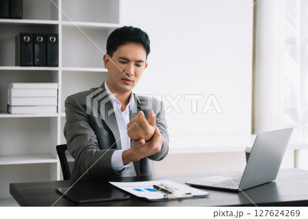 Overworked young Asian businessman office worker suffering from neck pain after had a long day at desk. office syndrome concept Overworked young Asian businessman office worker suffering from neck pain after had a long day at desk. office syndrome concept 127624269