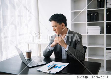 Confident Asian man with a smile standing holding notepad and tablet at the modern office. Confident Asian man with a smile standing holding notepad and tablet at the modern office. 127624301