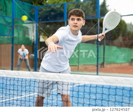 Young focused guy playing paddle tennis outdoors Young focused guy playing paddle tennis outdoors 127624587