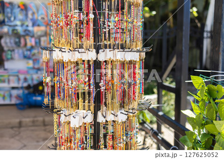 Colorful bead necklaces on tourist souvenir display. Summer travel, local craftsmanship, and coastal marketplace culture in Mediterranean street shops. 127625052
