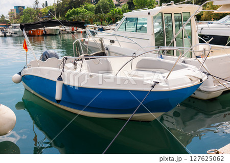 Small motorboats docked in calm marina water. Seaside lifestyle, coastal transportation, and nautical summer atmosphere Small motorboats docked in calm marina water. Seaside lifestyle, coastal transportation, and nautical summer atmosphere 127625062