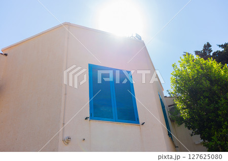 Blue shutter on beige wall. Mediterranean architecture, summer aesthetic, and coastal urban design with natural elements. 127625080