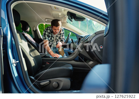 Man Cleaning Car Interior with Spray and Cloth Man Cleaning Car Interior with Spray and Cloth 127625922