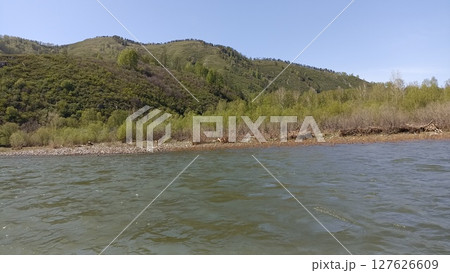 Verdant Mountain Landscape Reflected in Calm River Waters Under a Clear Blue Sky 127626609