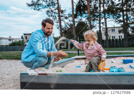 Father and little toddler son playing in the sandbox on playground. Father and little toddler son playing in the sandbox on playground. 127627086